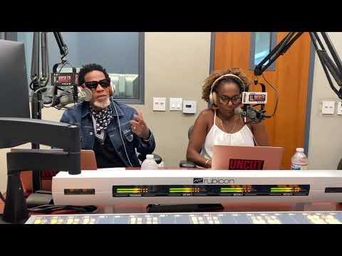 Hosts discussing live on air in a radio studio with microphones and computers.